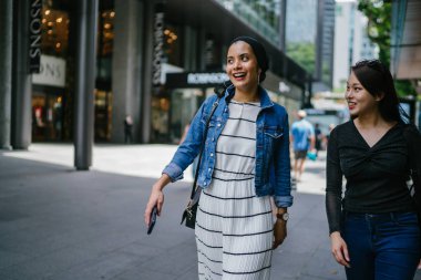 İki arkadaş, Orchard Road, Singapur, Asya 'da aydınlık bir yaz gününde mutlu bir şekilde yürüyüp konuşurlar. Biri Müslüman Malezyalı, diğeri Çinli bir kadın.. 
