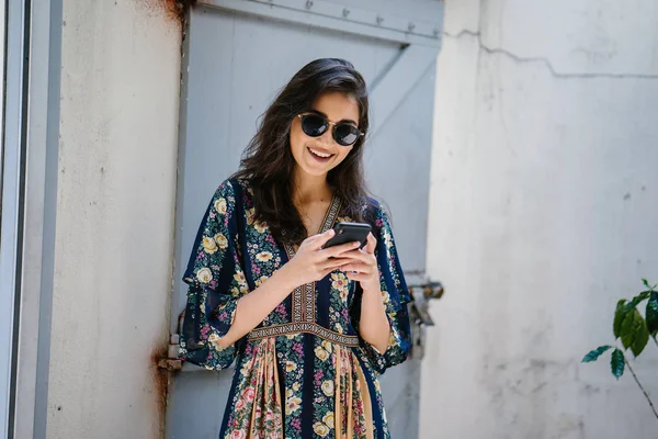 Bir elbise ve onun smartphone ile güneş gözlüğü takan bir genç, çekici ve güzel Hint Asyalı kadın portresi
