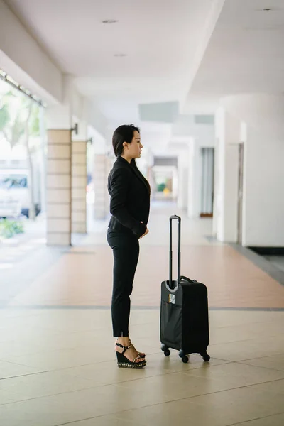 A young Asian woman is pulling her suitcase luggage. She is attractive, elegant and fashionably dressed