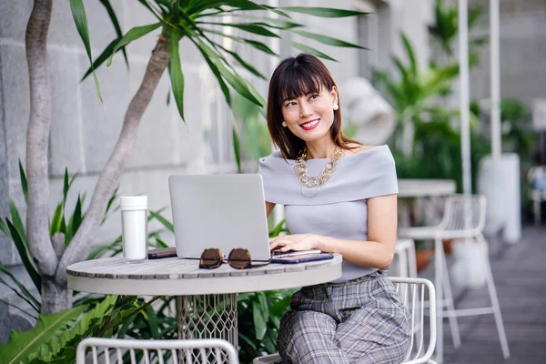 Modern dizüstü bilgisayar kullanarak çekici, kendine güvenen ve başarılı bir Çinli Asyalı kadının portresi