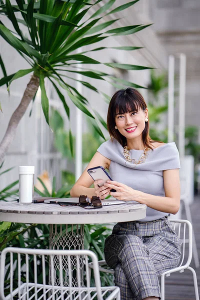 Çekici, kendine güvenen ve başarılı bir Çinli Asyalı kadının portresi. Akıllı telefonunu tutuyor. 