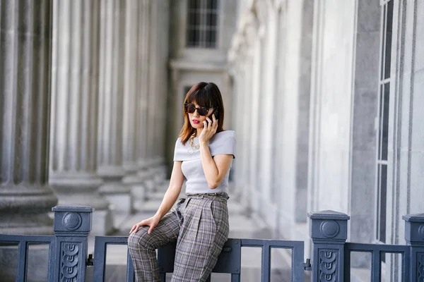 Çekici, kendine güvenen ve başarılı bir Çinli Asyalı kadının portresi. Akıllı telefonuyla konuşuyor. 