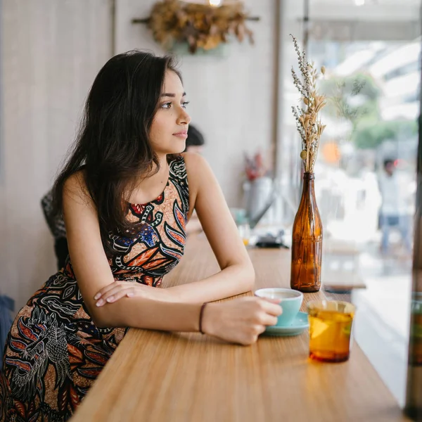 年轻美丽的印度亚裔新加坡妇女穿着印花礼服坐在咖啡馆里 享受周末在亚洲 — 图库照片