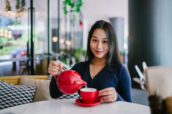 Bir açık havada açık havada oturan ve kırmızı bir çay seti çay sıcak bir fincan zevk genç, çekici, zarif ve güzel Asyalı kadın Portresi. 