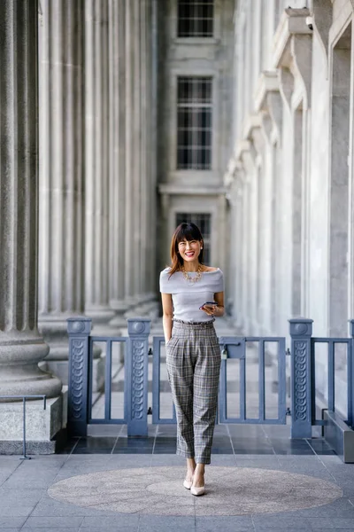 Çekici, kendine güvenen ve başarılı bir Çinli Asyalı kadının portresi. Akıllı telefonunu tutuyor. 