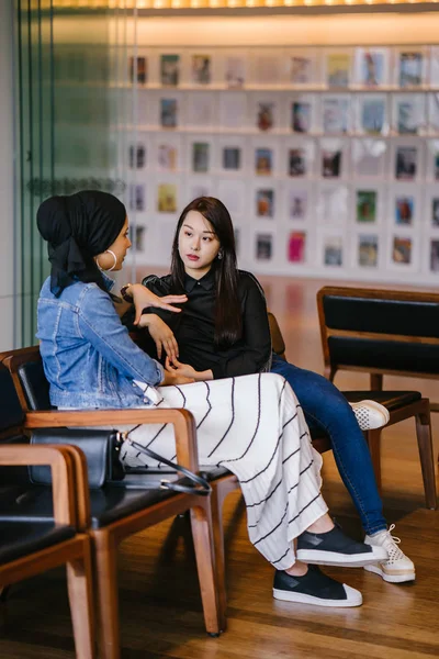 Duas Amigas Sentadas Banco Conversando Uma Delas Chinesa Outra Muçulmana — Fotografia de Stock