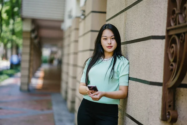 Akıllı telefon tutan genç ve güzel Asyalı bir Çinli kadının portresi.