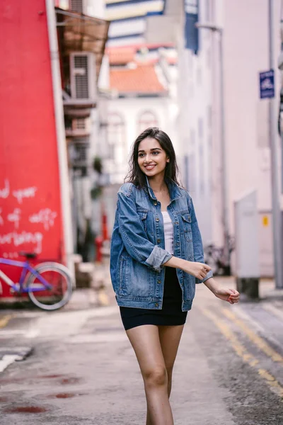 gün boyunca şehrin sokakta yürürken uzun boylu, genç ve zarif Hint Asyalı bir kadın. O bir retro Kot ceket giyiyor