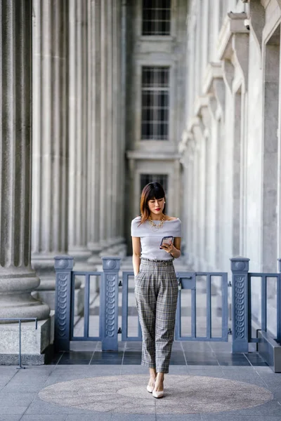 Çekici, kendine güvenen ve başarılı bir Çinli Asyalı kadının portresi. Akıllı telefonunu tutuyor. 