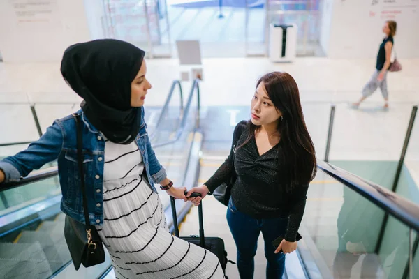 ショッピングモールにいる2人の女性の友人のうち1人は中国人でもう1人はイスラム教徒です — ストック写真