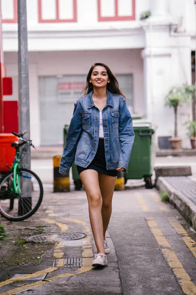 gün boyunca şehrin sokakta yürürken uzun boylu, genç ve zarif Hint Asyalı bir kadın. O bir retro Kot ceket giyiyor