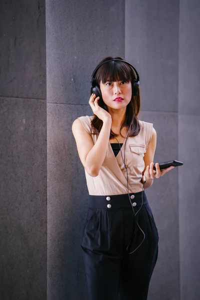 Onun kulaklık müzik dinlemek orta yaşlı, fotojenik bir Çinli kadın portresi