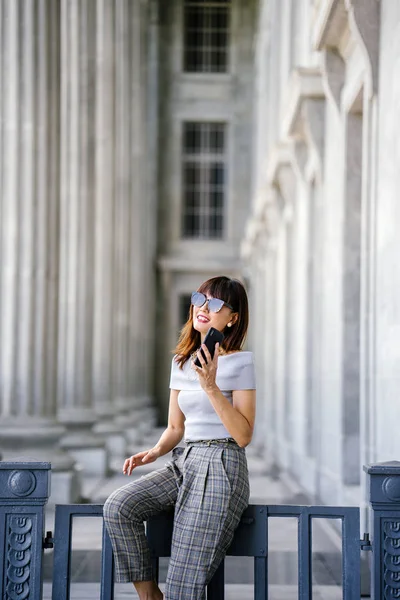 Çekici, kendine güvenen ve başarılı bir Çinli Asyalı kadının portresi. Akıllı telefonunu tutuyor. 