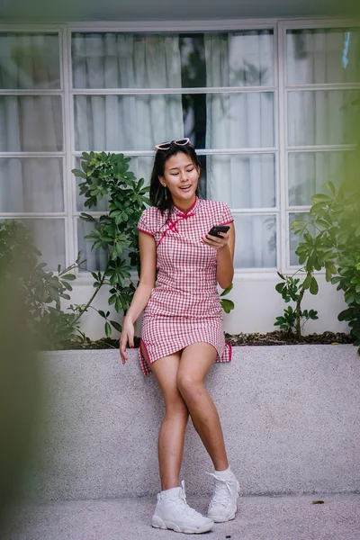 Bir genç, çok-cool-için-okulu Asya retro kırmızı ve beyaz cheongsam genç kız elbise gün boyunca bir kenarında oturan Çin moda portre