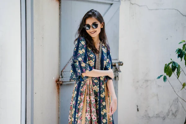 uzun boylu, zarif ve güzel Hint Asyalı kadın yaz elbise ve güneş gözlüğü gülümsüyor o pozlar gün boyunca bir arka sokakta bir sokakta olarak içinde