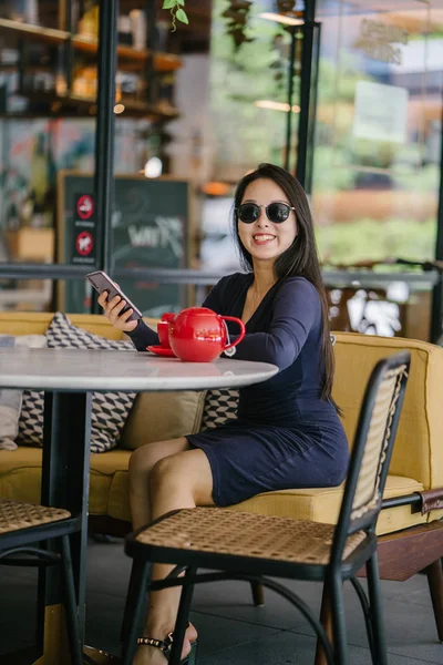 一个年轻 优雅和美丽的亚洲妇女坐在户外露天咖啡馆 从红茶具中享用热茶的肖像 — 图库照片