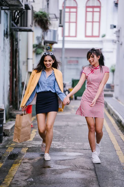 iki yakın arkadaş birlikte bir ara Sokaktan yürürken. Onlar birlikte mutlu bir şekilde yürürken onlar hem trendy retro giyim ve tutuşup giyiyorsun. Çince, diğer Hint biri