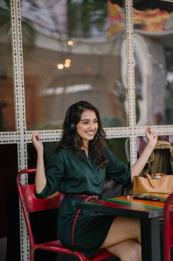 Genç Hintli Asyalı kadın o onun Smartphone-e doğru onun kulaklık streaming müzik hoşlanır