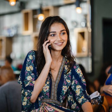 Bir kafede onu smartphone o görüşmeler olarak gündüzleri çatık bir genç ve çekici Hint Asyalı kadın portresi