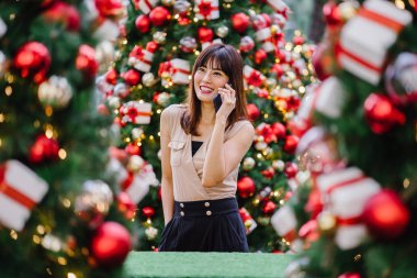 güzel orta yaşlı kadın mutlu onun smartphone üzerinde konuşuyor ve aynı derecede o durgunluk ortasında güzel gülümseyen gün boyunca Noel ağaçları dekore edilmiş olan