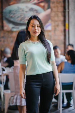 Gündüz vakti genç, seksi ve çekici bir Asyalı kadının portresi. O nane yeşili bir kazak giyiyor.