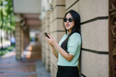Akıllı telefon tutan genç ve güzel Asyalı bir Çinli kadının portresi.