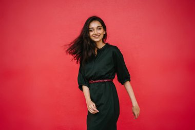 Stüdyo bir güzel, Genç ve çekici Hint Asyalı kadın kırmızı studio çerçevede bir portresi. O zarif bir basit yeşil elbise ve kırmızı kuşak giymiş ve gülüyor.