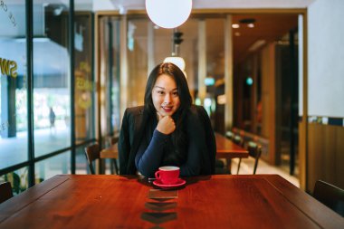 Bir açık havada açık havada oturan ve kırmızı bir çay seti çay sıcak bir fincan zevk genç, çekici, zarif ve güzel Asyalı kadın Portresi. 