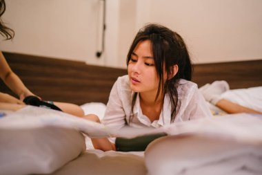 İki genç Asyalı arkadaş bir pansiyonda bir yatakta oturuyor. İkisi de Asyalı ve birlikte seyahat ediyorlar. Biri Hintli, diğeri Çinli. İkisi de gündelik giysiler içinde ve odalarında dinleniyorlar..