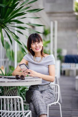 Çekici, kendine güvenen ve başarılı bir Çinli Asyalı kadının portresi. Akıllı telefonunu tutuyor. 