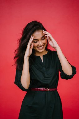 Stüdyo bir güzel, Genç ve çekici Hint Asyalı kadın kırmızı studio çerçevede bir portresi. O zarif bir basit yeşil elbise ve kırmızı kuşak giymiş ve gülüyor.