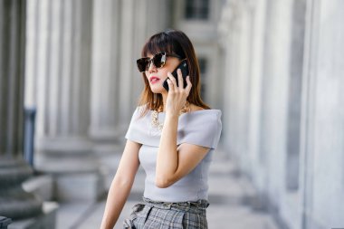 Çekici, kendine güvenen ve başarılı bir Çinli Asyalı kadının portresi. Akıllı telefonuyla konuşuyor. 