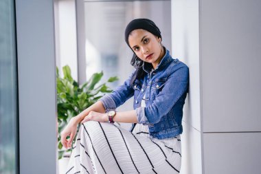 Genç, zarif ve çekici Malezyalı Müslüman kadın gün boyunca elbise ve kot ceket giyiyor..