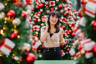 Gün boyunca birkaç süslü Noel ağaçları arasında duran zarif ve çekici bir orta yaşlı kadın portresi