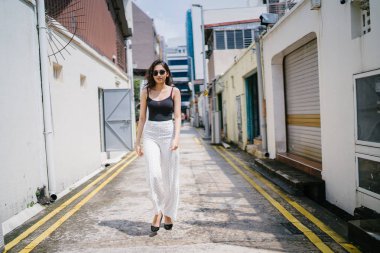 Genç, uzun boylu, ince ve zarif Hint Asyalı kadın rahat bir kıyafet içinde Asya bir sokakta bir sokakta aşağı gün boyunca yürür