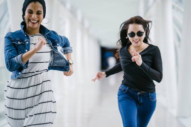 İki farklı arkadaş, iyi aydınlatılmış beyaz fütüristik bir üstgeçit köprüsünden kameraya doğru koşuyorlar. Biri Müslüman bir Orta Doğulu kadın, diğeri de Çinli..