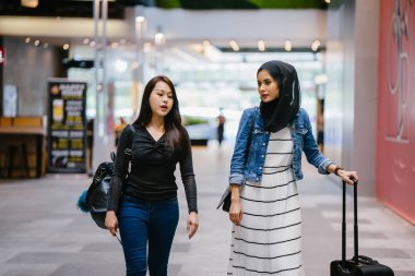 İki arkadaş, Orchard Road, Singapur, Asya 'da aydınlık bir yaz gününde mutlu bir şekilde yürüyüp konuşurlar. Biri Müslüman Malezyalı, diğeri Çinli bir kadın.. 