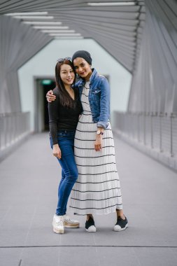 Gündüz vakti köprüde farklı etnik kökenlere sahip iki arkadaş. Biri Malezyalı Müslüman bir kadın, diğeri de Çinli bir Asyalı. İkisi de genç, enerjik ve çekici..