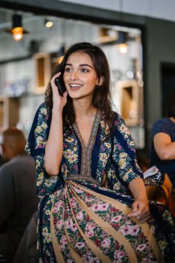 Bir kafede onu smartphone o görüşmeler olarak gündüzleri çatık bir genç ve çekici Hint Asyalı kadın portresi