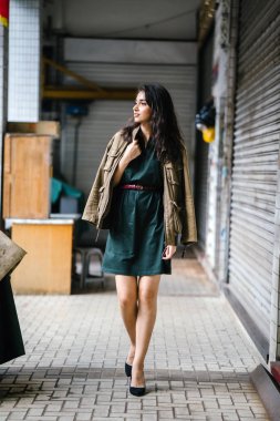 Hint Asyalı kadın Genç, uzun boylu, ince ve zarif bir portre için poz veriyor. O rahat ve şık rahat giysiler giyiyor ve bir adamın ceketi omuzları üzerinde bol dökümlü vardır. 