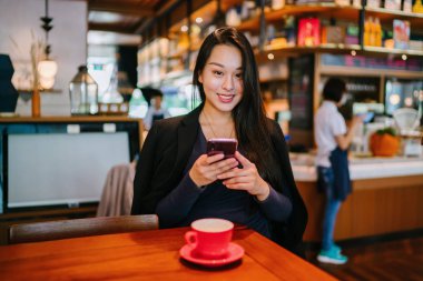 Bir açık havada açık havada oturan ve kırmızı bir çay seti çay sıcak bir fincan zevk genç, çekici, zarif ve güzel Asyalı kadın Portresi. 