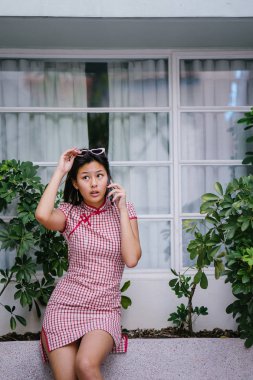 Bir şık, güzel ve genç genç Asyalı kız onun smartphone üzerinde konuşuyor. Geleneksel Çince elbise giyiyor 