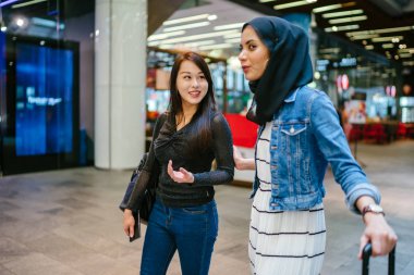 İki arkadaş, Orchard Road, Singapur, Asya 'da aydınlık bir yaz gününde mutlu bir şekilde yürüyüp konuşurlar. Biri Müslüman Malezyalı, diğeri Çinli bir kadın.. 