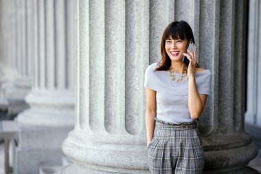 Çekici, kendine güvenen ve başarılı bir Çinli Asyalı kadının portresi. Akıllı telefonunu tutuyor. 