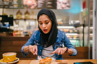 Genç bir kadın kahvaltını kafede yapıyor.