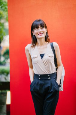 Bir çalışma hanım o pozlar ve onun baş shot kırmızı bir arka plan için gülümsüyor olarak stüdyo portresi