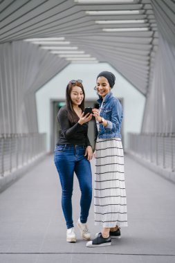 Gündüz vakti köprüde farklı etnik kökenlere sahip iki arkadaş. Biri Malezyalı Müslüman bir kadın, diğeri de Çinli bir Asyalı. İkisi de genç, enerjik ve çekici..