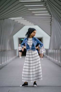 Genç, zarif ve çekici Malezyalı Müslüman kadın gün boyunca elbise ve kot ceket giyiyor..