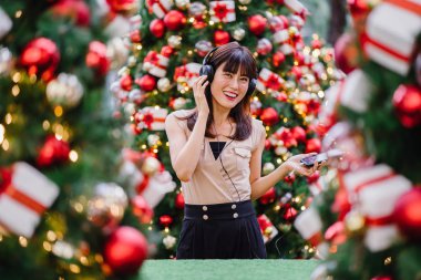 Gün boyunca birkaç süslü Noel ağaçları arasında duran zarif ve çekici bir orta yaşlı kadın portresi