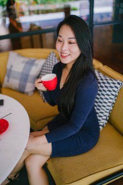 Bir açık havada açık havada oturan ve kırmızı bir çay seti çay sıcak bir fincan zevk genç, çekici, zarif ve güzel Asyalı kadın Portresi. 